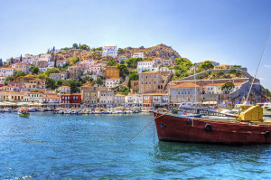 A view of the beautiful Greek island, Hydra. There is a fishing boat on the foreground and some local architecture on the background. The view is from the sea as the cruise ship embarked in Hydra.